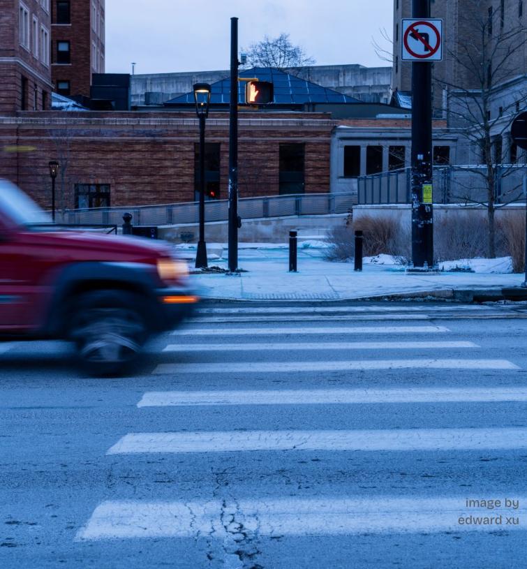 Color image of a red truck moving toward a cross-walk