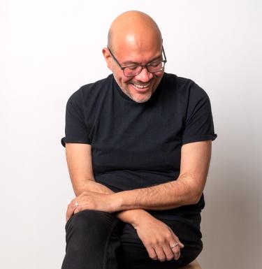 Jose Santiago Perez sitting with arms crossed and smiling